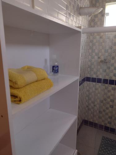 伊塔帕里卡Casa Girassol的浴室设有白色的架子和黄色的毛巾