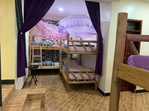 MpigiMpanga Nature Center的客房设有三张双层床和紫色窗帘