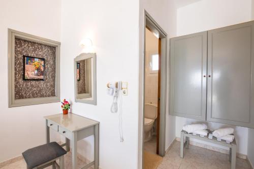 阿莫皮Perama Hotel, Karpathos的一间带卫生间、桌子和橱柜的浴室