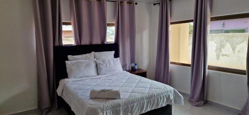 MuseleShalom Apartments Kalumbila的一间卧室配有一张大床和紫色窗帘