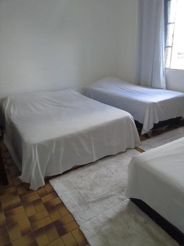 科伦巴LINDO APTO CENTRAL, MOBILIADO, AO LADO DO HOTEL NACIONAL CORUMBÁ -MS的客房内的两张床和白色床单