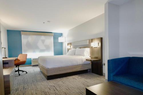 史密斯菲尔德Holiday Inn Express & Suites - Smithfield/Selma, an IHG Hotel的一间卧室配有一张床、一张桌子和一把椅子