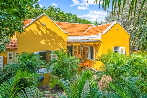 威廉斯塔德Curaçao Gardens的棕榈树前方的黄色房子