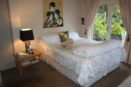 MaungatapuThe Beach House Bed and Breakfast的一间卧室配有一张床和一张带台灯的桌子