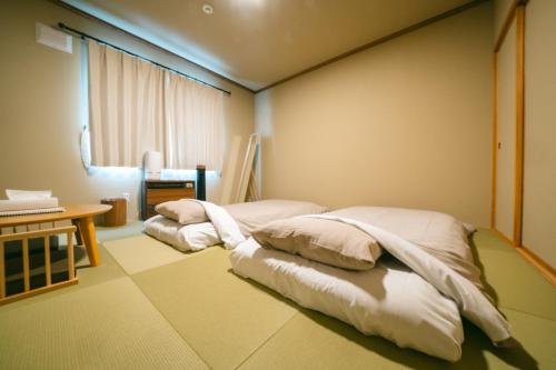 弟子屈町TESHIKAGA HOSTEL MISATO的配有桌子和窗户的客房内的两张床