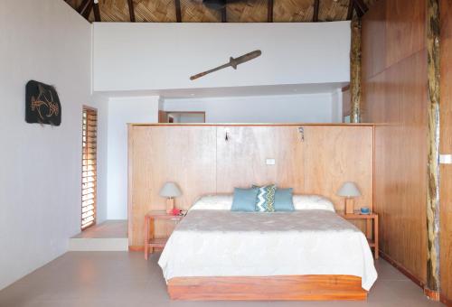 Toberua托伯岛度假酒店的一间卧室配有一张带木制床头板的床