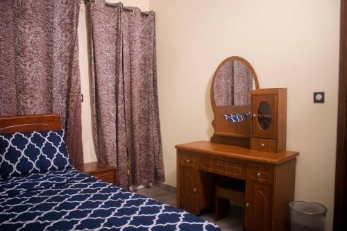 瓦加杜古Kadoued Furnished Apartment 2 Bedroom的一间卧室配有一张床、梳妆台和镜子