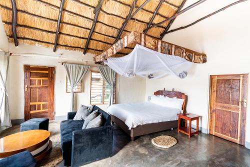 KakumbiNjobvu Safari的一间卧室配有一张床、一张沙发和一张桌子