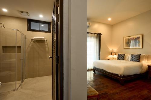 清迈Teera villa chiang mai ทีร่าวิลล่าเชียงใหม่的一间卧室设有一张床和一个玻璃淋浴间