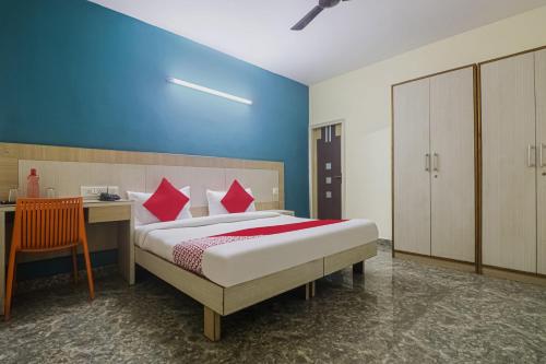 古尔冈Capital O Hotel Crown Inn Near Appu Ghar的一间卧室配有一张带红色枕头的床和一张书桌