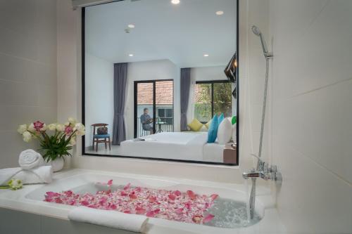 暹粒Angkor Aurora的浴室配有装满粉红色花卉的浴缸。