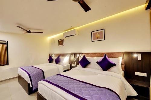 班加罗尔The Lavender Hotel的两张位于酒店客房的床铺,配有紫色枕头