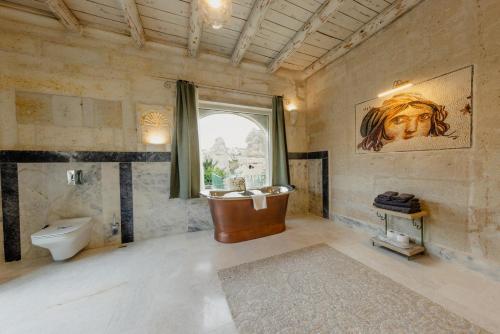 格雷梅Aza Cave Cappadocia Adult Hotel的带浴缸、卫生间和窗户的浴室