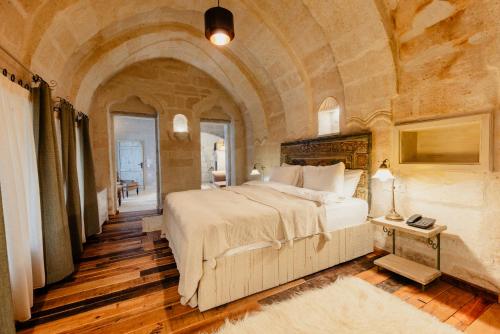 格雷梅Aza Cave Cappadocia Adult Hotel的卧室配有一张石墙内的大床