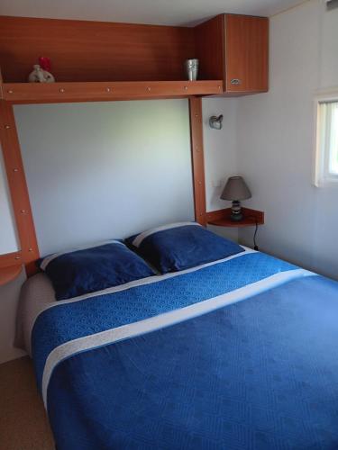 LombezMobilhome cosy au calme de la campagne的一间卧室配有一张带蓝色棉被的床