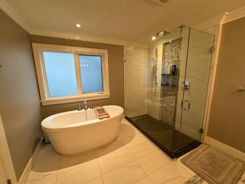 温哥华Charming Modern Home Near Downtown and UBC的带浴缸和玻璃淋浴间的浴室。