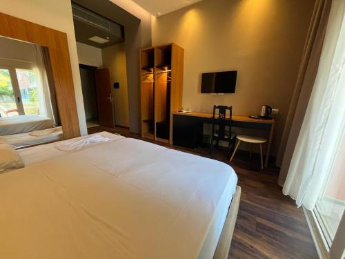 都拉斯Olivia's Hill Resort的一间卧室配有一张床和一张书桌及电视