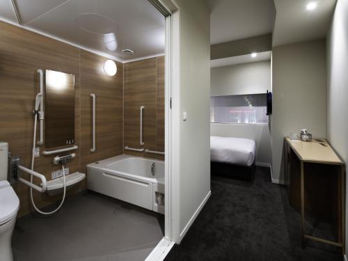 东京新宿格兰贝尔酒店的带浴缸和卫生间的浴室以及1张床。