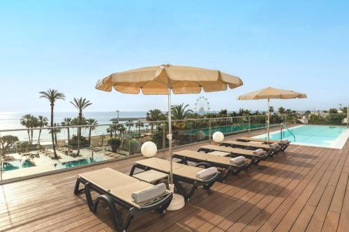 多列毛利诺斯Hotel Ocean House Costa del Sol, Affiliated by Meliá的一个带椅子和遮阳伞的甲板和一个游泳池