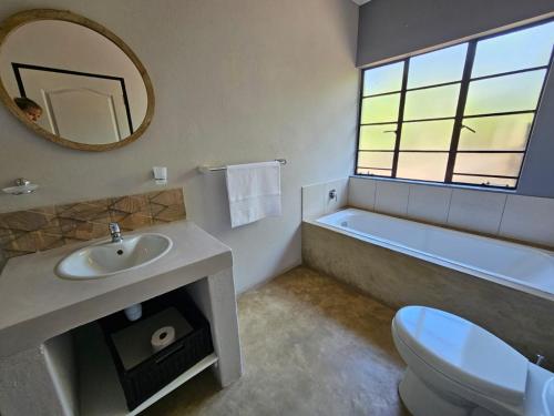 侯斯普瑞特The Blyde Canyon House的一间带水槽、浴缸和镜子的浴室