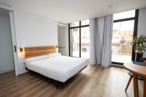 曼雷沙APM Manresa的卧室设有白色的床和大窗户