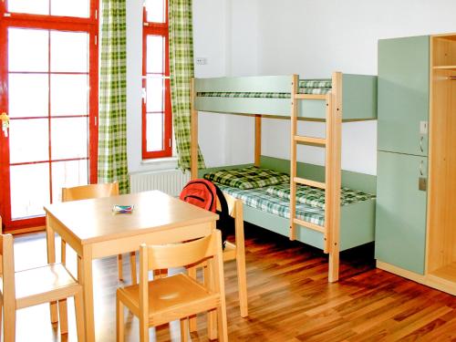 莱比锡Sleepy Lion Hostel & Apartments Leipzig的客房设有一张桌子和一张双层床。