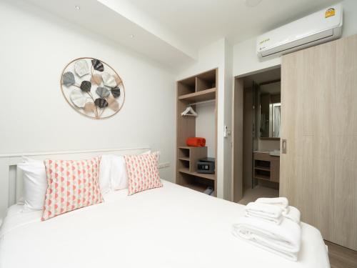 邦涛海滩Family 2bd apartments in Laguna SkyPark的卧室配有白色的床和墙上的时钟