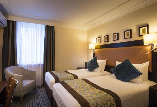 希灵登伦敦希思罗机场5号航站楼提斯特尔酒店的酒店客房,配有两张床和椅子