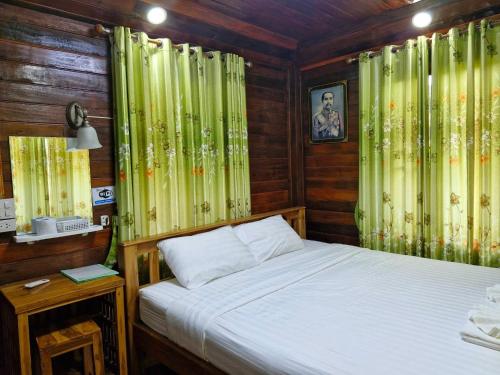 Ban KoYungthong Baan Suan Resort的一间卧室配有一张带绿色窗帘的床