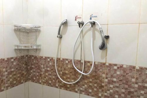 日惹Capital O 93882 The Pondok Palma Villa & Resto的浴室内墙上的软管淋浴
