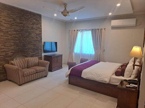伊斯兰堡Welcome Hotel Islamabad的一间卧室配有一张床、一把椅子和电视