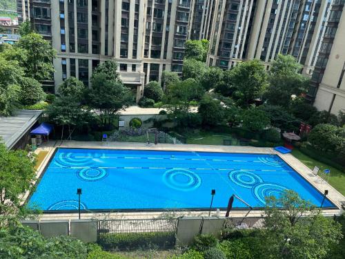 张家界Pikkie Designer's Stylish Three Bed Room Apartmemt的一个大型蓝色游泳池,其建筑背景为: