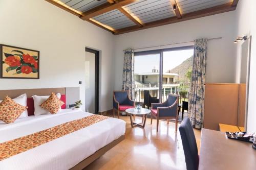 乌代浦Banjara Hills Jungle Lodge的酒店客房带一张床、一张桌子和椅子