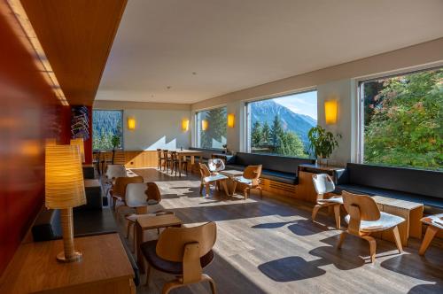 伦策海德Valbella-Lenzerheide Youth Hostel的餐厅设有桌椅和大窗户。
