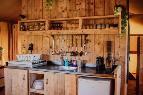 赫劳Glamping-tent 'Yatra Nirvana' met privé keuken en regendouche的厨房设有木墙和带水槽的台面。