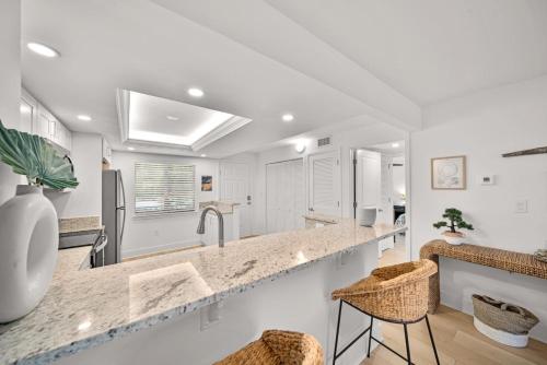 萨尼贝尔Loggerhead Cay #401的厨房设有白色的墙壁和带凳子的台面