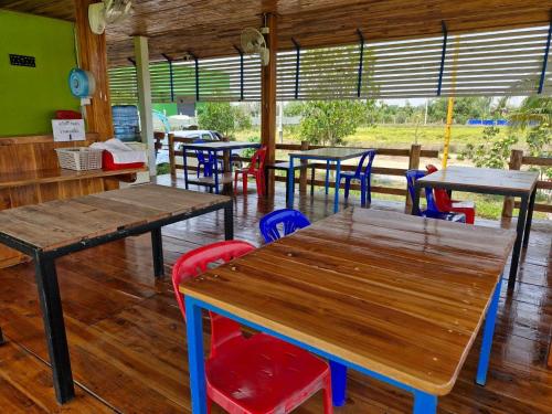 Ban KoYungthong Baan Suan Resort的餐厅设有木桌和五颜六色的椅子