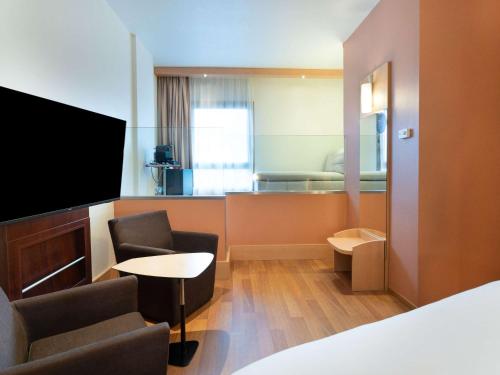 马德里马德里拉斯本塔斯宜必思酒店的酒店客房带一张床、一台电视和椅子