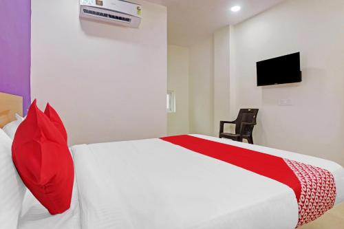 Haidar SāhibgūdaLangar Houz Near Golconda Fort的一间卧室配有一张带红色枕头的白色床和电视。