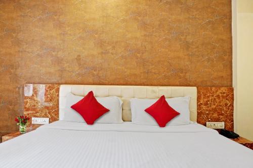 LukerganjOYO Flagship Bliss Inn的卧室配有带红色枕头的白色床
