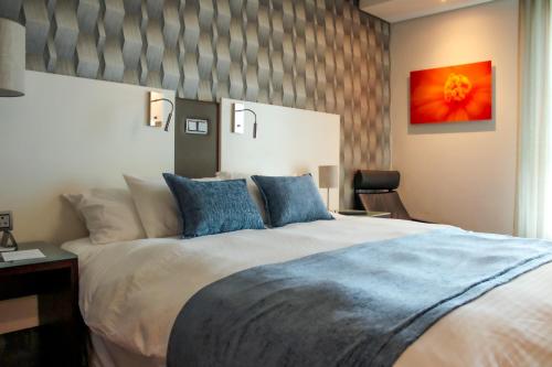 MatroosfonteinHotel Verde Cape Town Airport的一间卧室配有一张带蓝色枕头的大床