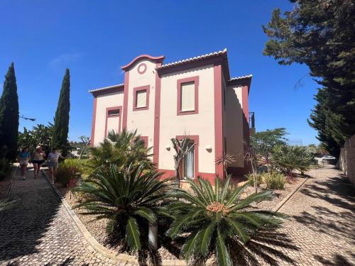 埃斯坦巴Vale da Pinta Golf的一座粉红色的房子,前面有棕榈树