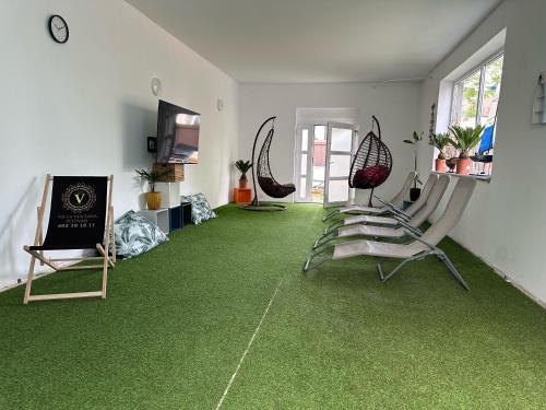 波兹南Villa Ventana 2 City Free Parking Śniadanie w cenie 503 18 18 11的客房铺有绿色地毯,配有椅子和电视。