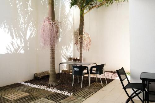 卡尼索GuestReady - Charming Caniço Retreat的一间设有桌子和两棵棕榈树的用餐室