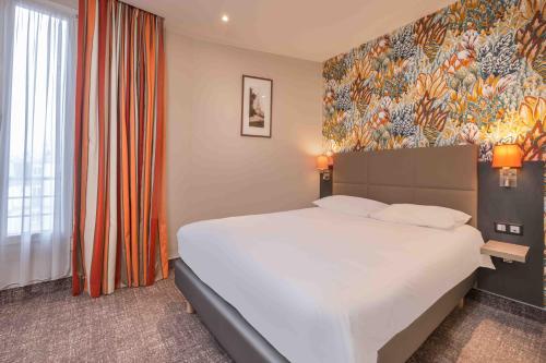 巴黎Terminus Orléans Paris的一间卧室设有一张大床和色彩缤纷的墙壁