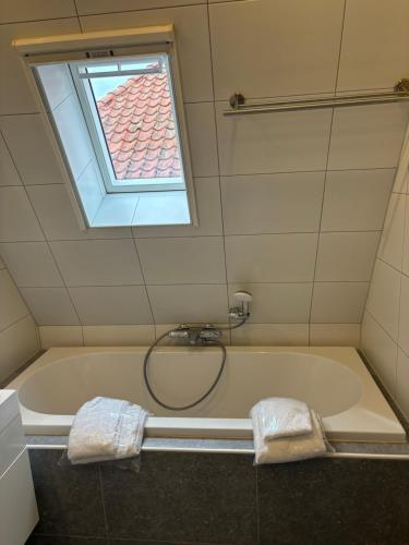 希格Appartementen De Helling 44的带浴缸和窗户的浴室