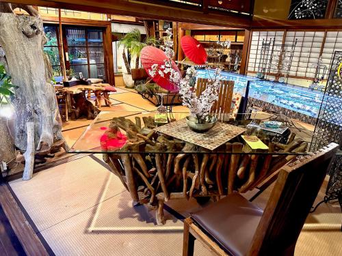 松山考米卡麦哈玛民宿的一间设有花卉和遮阳伞的玻璃桌的房间
