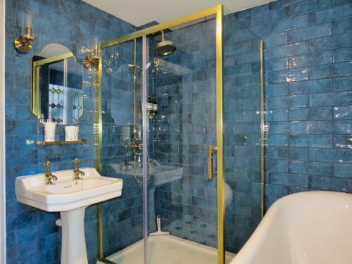 埃文河畔布拉德福The Hall的蓝色瓷砖浴室设有水槽和淋浴