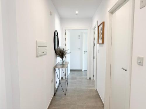 直布罗陀E1 Suites & Spa aparthotel style - Gym & Spa的走廊上设有白色的墙壁和一张桌子上的镜子