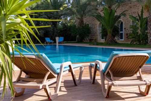 哈马马特Hôtel Dar Mhana的游泳池旁的两把椅子